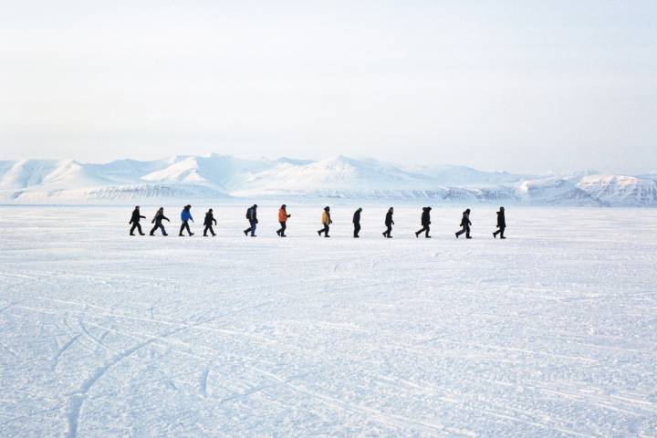 figures walk on ice in a vast Arctic landscape