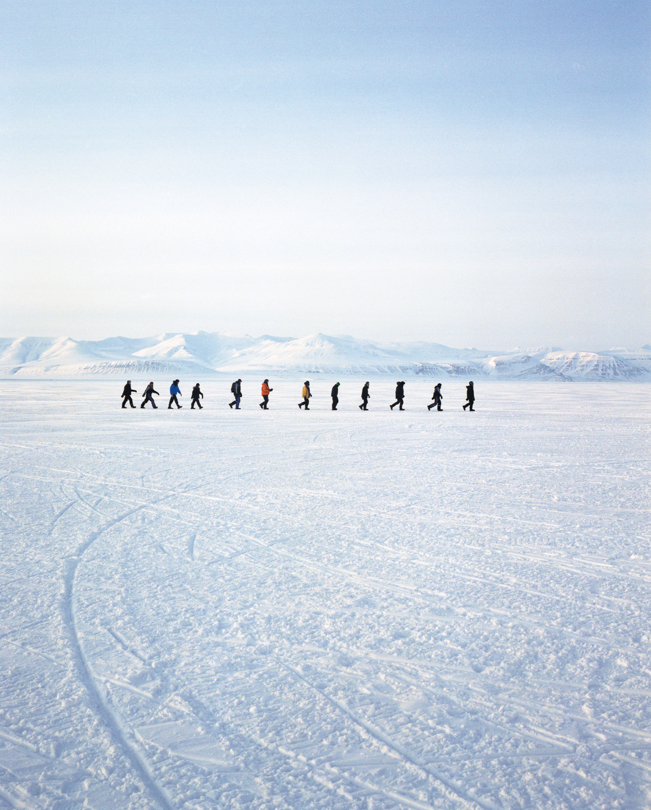 figures walk on ice in a vast Arctic landscape