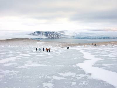 tiny figures walk on an ice sheet