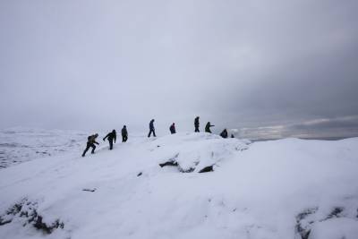 group of people climb an arctic hill